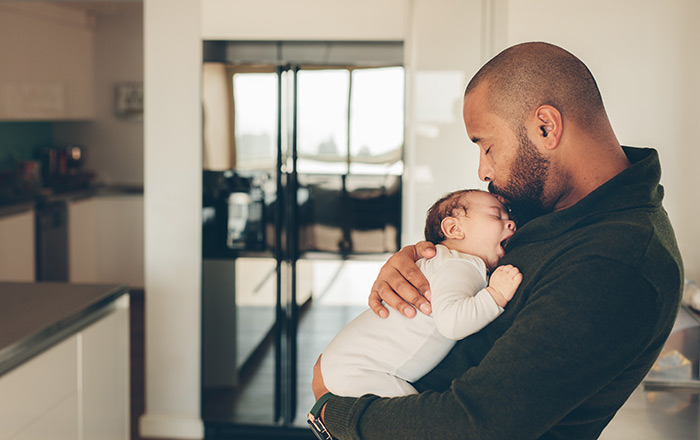 Father holding newborn baby in kitchen.