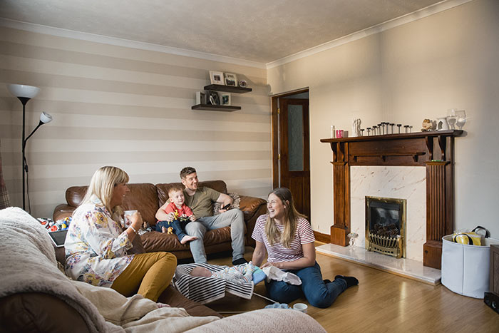 Grandmother visiting family with new baby in living room.