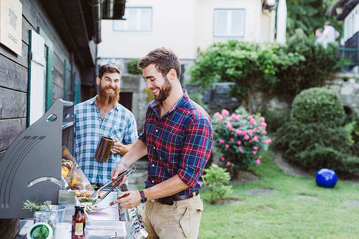 Men grilling food in backyard.