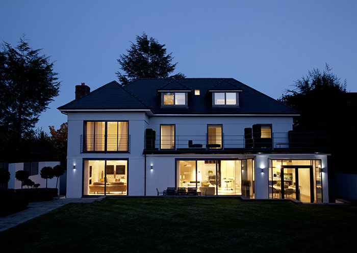 Modern white home at night with lighting.