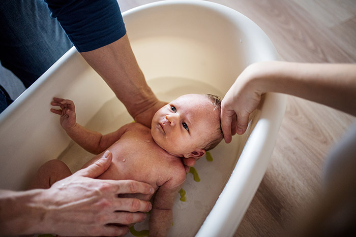 Parents giving newborn baby a bath.