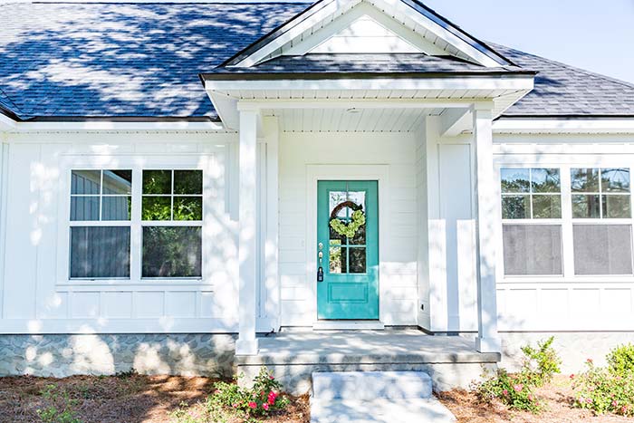 Small front porch on modern white farmhouse with blue front door.