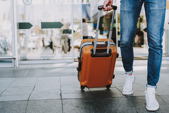 Traveler rolling suitcase out of airport.