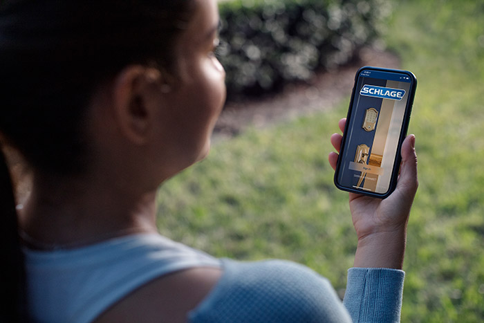 Woman looking at Schlage Home app on mobile phone.