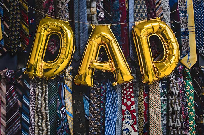 Gold dad balloons in front of background of ties.