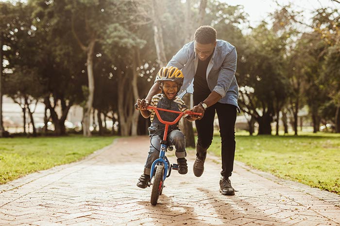 Dad teaching son to ride bicycle.