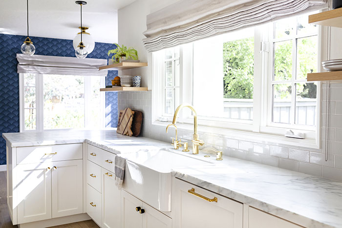 Modern farmhouse kitchen with white cabinets, brass hardware and marble countertops.