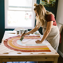 Pregnant woman painting rainbow textile