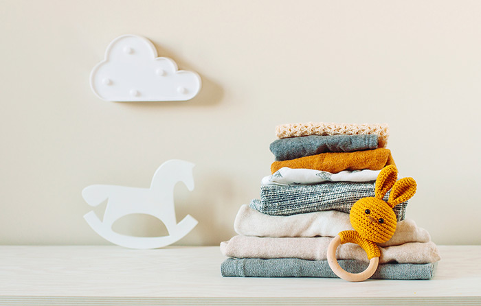 Stack of neutral baby linens and baby rattle.