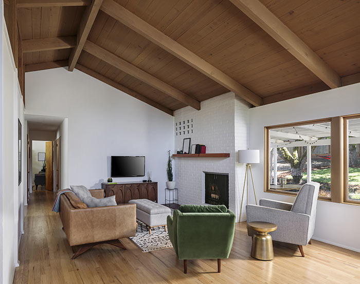 Mid-century modern living room with brown leather couch and green velvet chair