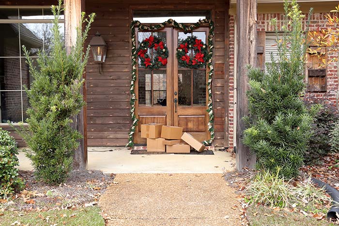 Pile of packages on front porch decorated for the holidays.