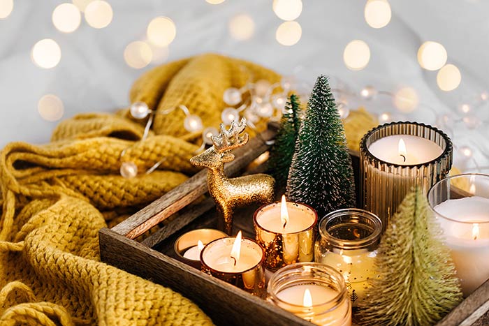 Burning candles with Christmas decorations on wooden tray.