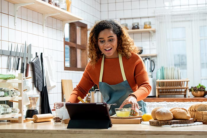 Woman cooking in the kitchen while looking at iPad.