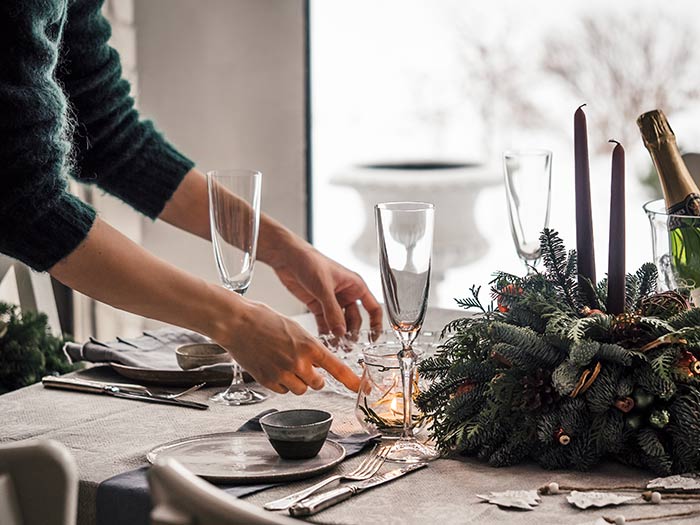 Woman setting table for holiday dinner party.