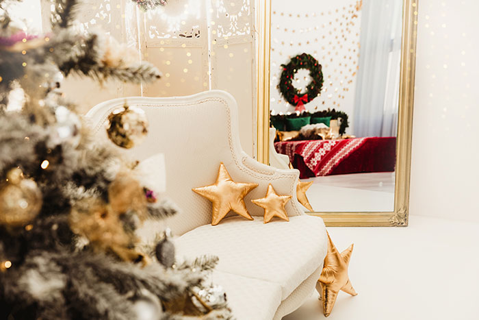 Glamorous Christmas decor next to large gold framed floor mirror.