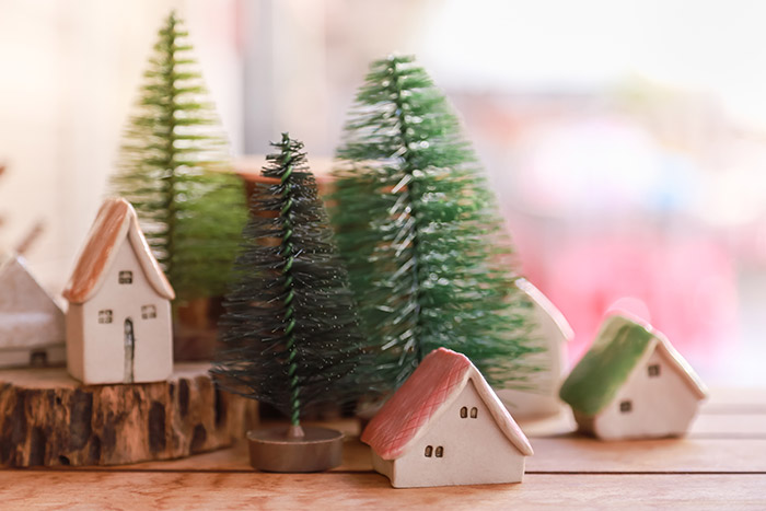 Tiny clay houses next to bottle brush trees.