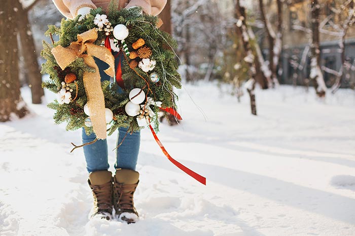 Woman holding Christmas wreath in the snow.