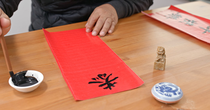 Man painting chinese calligraphy for lunar new year.