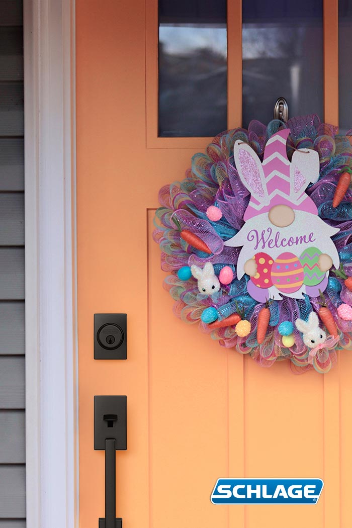 Orange front door with Easter wreath and matte black Schlage door handleset.