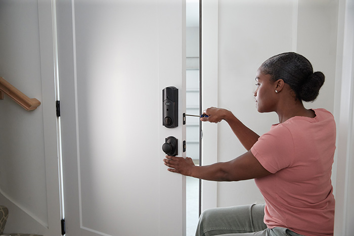 Woman replacing front door lock with Schlage smart lock.