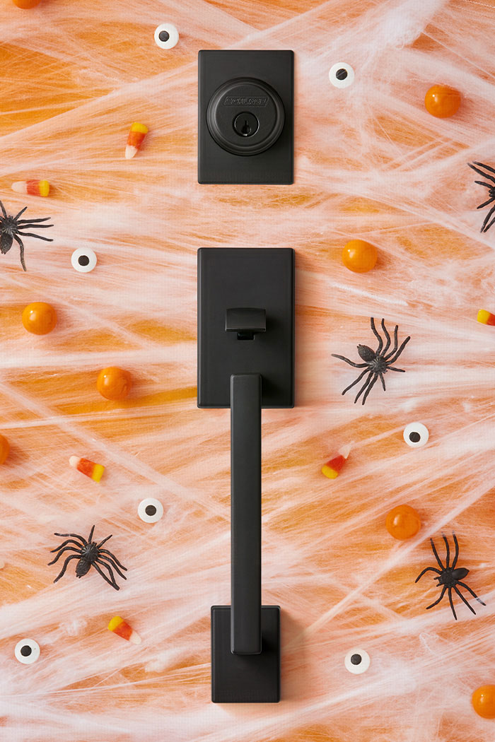 Schlage Matte Black Century handleset flatlay with Halloween decor.