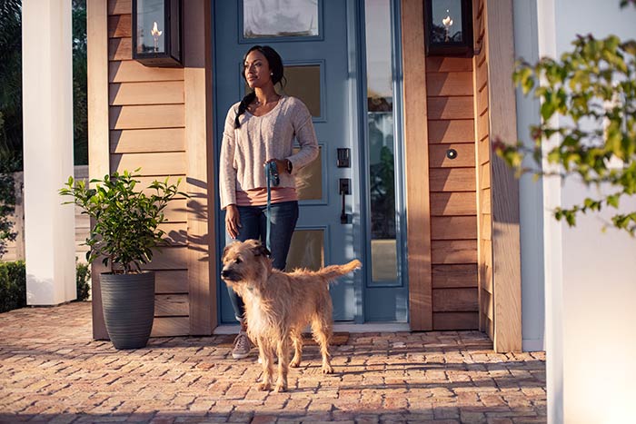 Woman leaving home to walk dog after locking front door with Schlage smart lock.