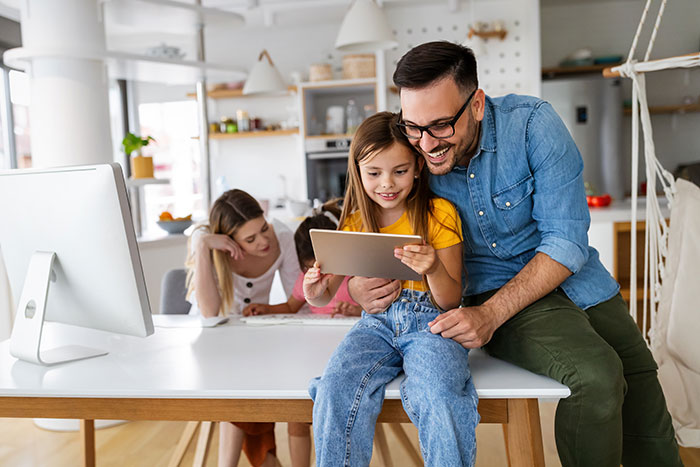 Young family sitting around table looking at smart home devices.