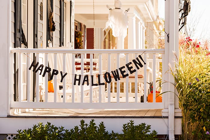 Halloween porch decor with Happy Halloween banner hanging on front porch railing.