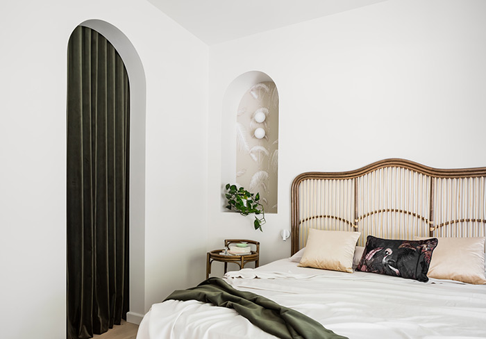 Bedroom with arched doorways and velvet drapes.