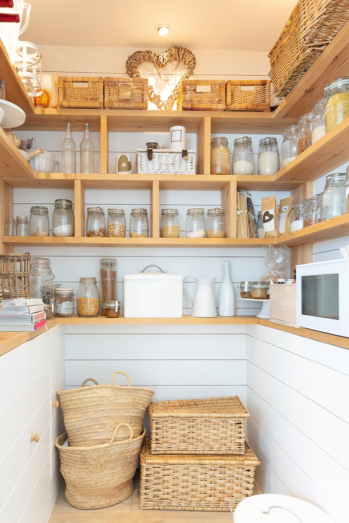Neutral farmhouse kitchen pantry organized with woven baskets and jars.