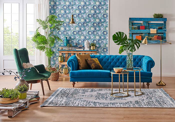 Playful living room with velvet furniture and abstract wallpaper.