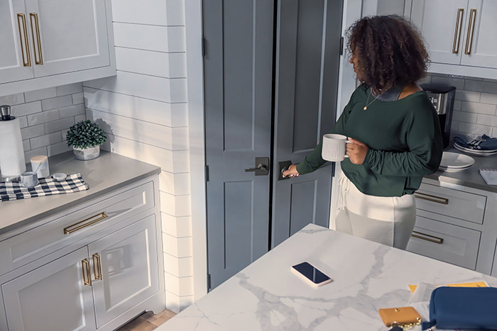 Woman in kitchen opening modern farmhouse pantry door handle from Schlage.