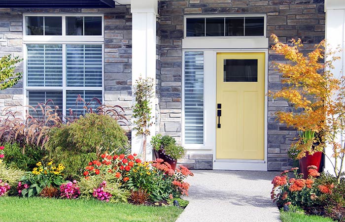 Suburban stone home with pale yellow front door and matte black front door handle.