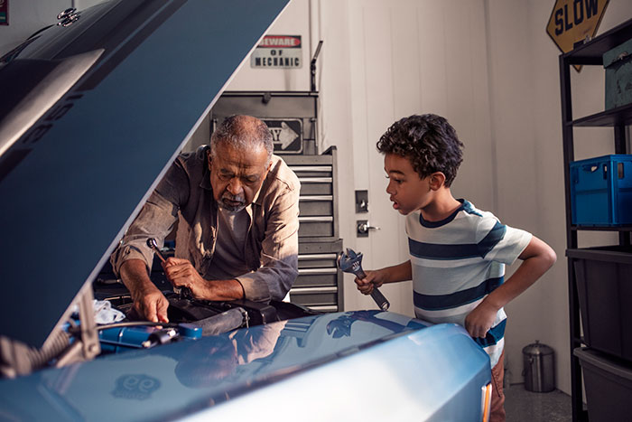 Grandfather and grandson working on car in the garage with Schlage Encode smart lock on garage door.
