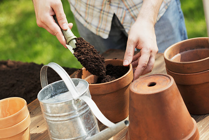 Man filling flower pot with potting soil.