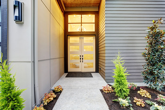 Modern home with neutral natural wood front door and matte black door handle.