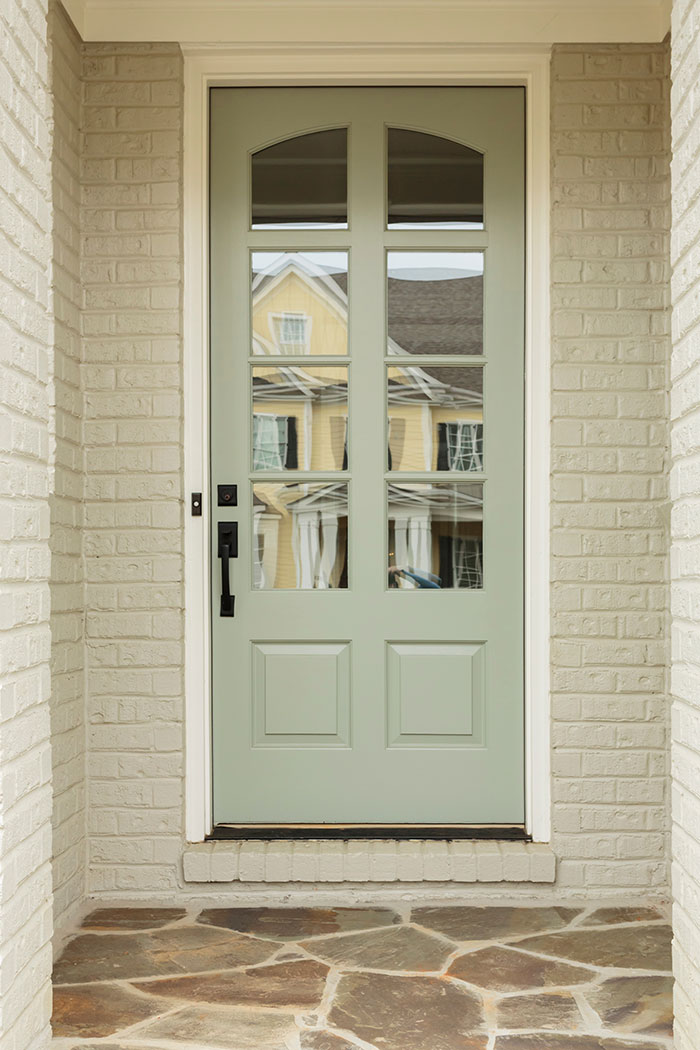 White brick home with neutral sage green front door.