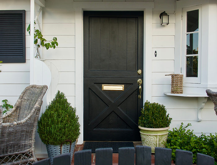 Cottage style black dutch door with brass door handle.
