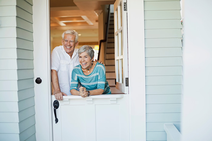 Happy couple standing at open dutch door.