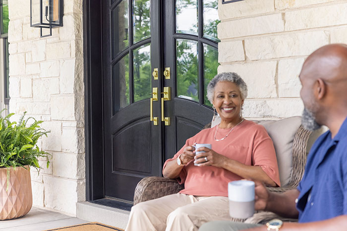 Independent living couple sitting on front porch with coffee.