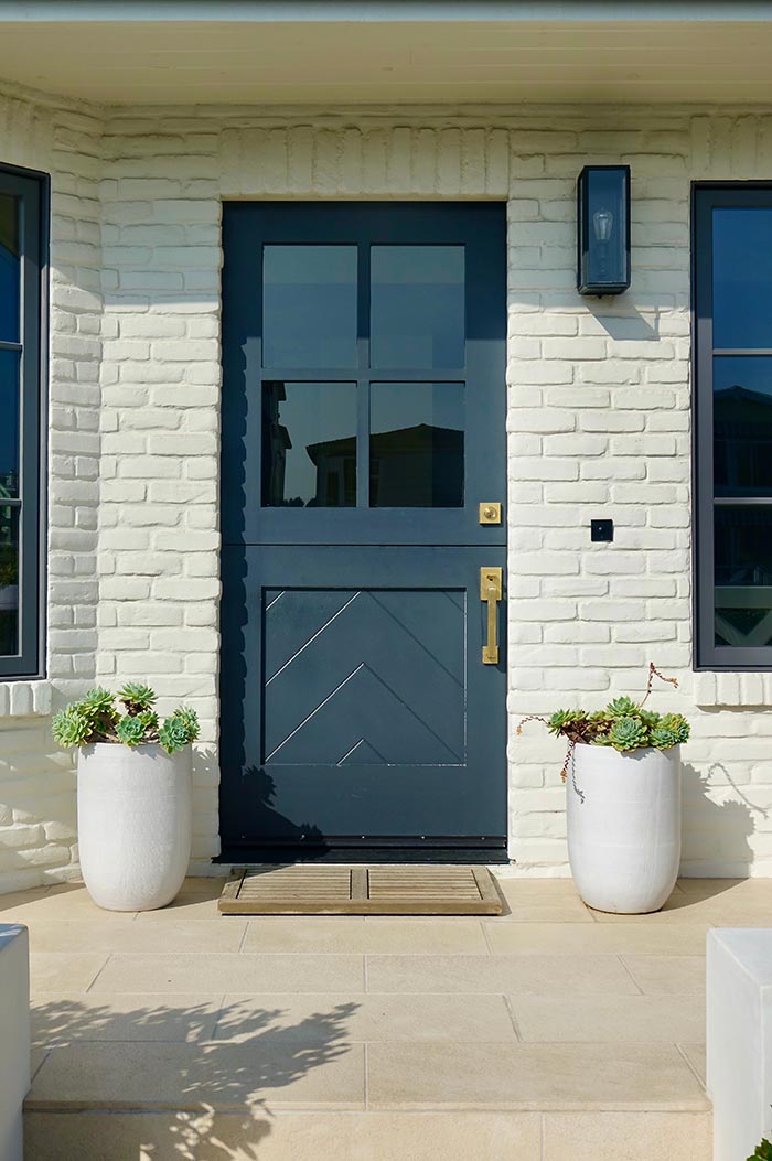 Teal blue dutch door on ivory brick home with satin brass handleset.