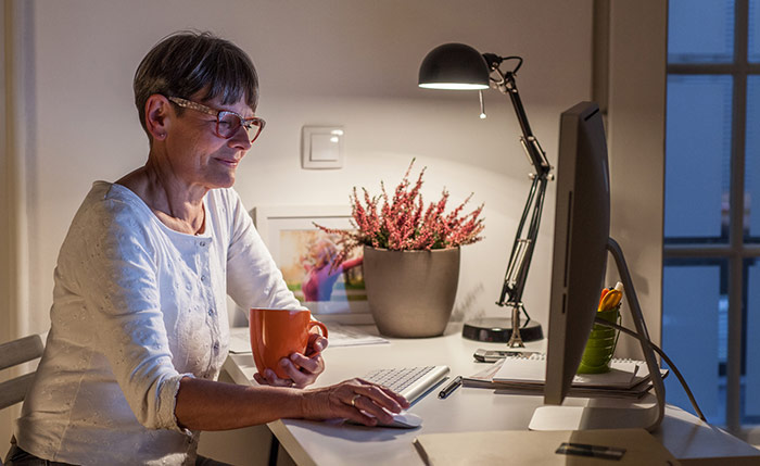 Woman working late from home office holding coffee mug.