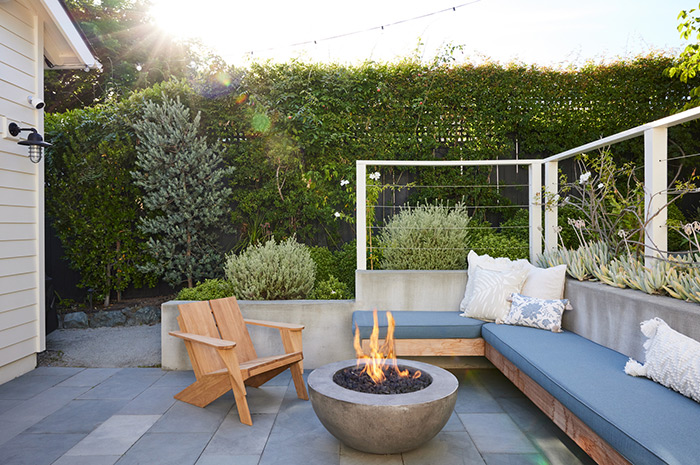 Modern backyard deck patio with concrete fire pit and wall of greenery for privacy.