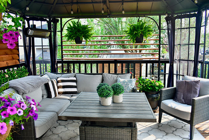 Screened-in backyard deck with hanging ferns and wooden slats for privacy.