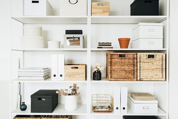 Stylish organized minimalist shelving unit with baskets, boxes, eucalyptus.
