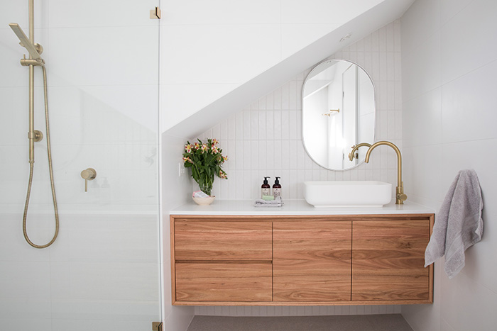 Modern Scandinavian bathroom with white tile walls and brass hardware finishes for bathroom.