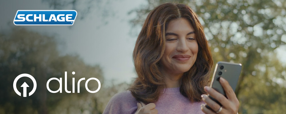 woman with smart phone unlocking her front door deadbolt powered by the Aliro 1.0 standard