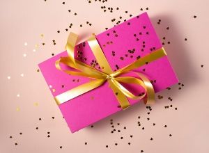 Pink gift box wrapped with gold bow.
