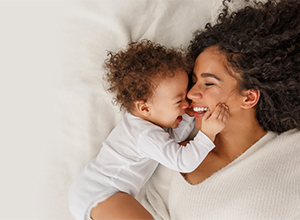 Mother and baby smiling at each other while laying down.