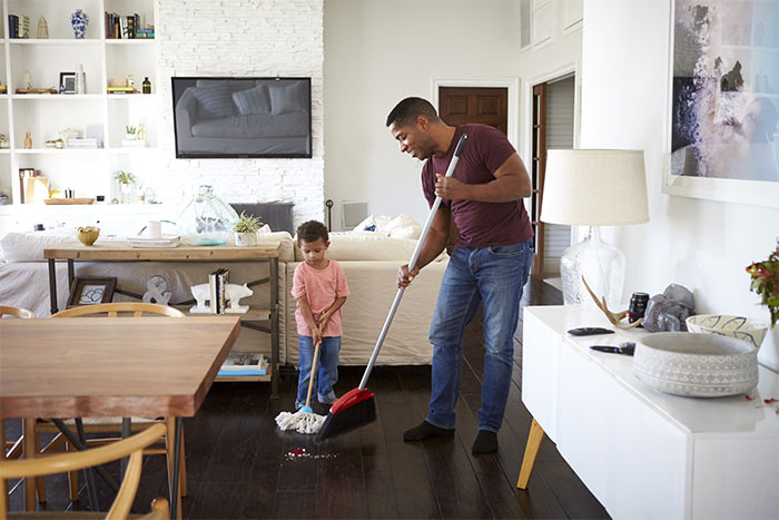 Father and son sweeping the floor.